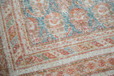 Distressed Turkish Oushak carpet corner: faded terra cotta, blanched teal, neutral beige.