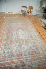 Corner of distressed Oushak rug, showing faded cinnabar, teal patterns, and textured surface.