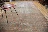 Distressed Oushak carpet with time-softened terracotta and blanched teal botanical motifs.