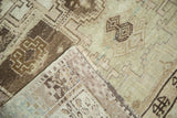 Folded hand-knotted Oushak rug showing geometric patterns, wooded tones, and reverse weave.