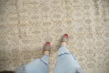 Distressed Oushak carpet, blanched ivory field with charcoal vinery and floral panels.
