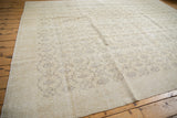 Distressed Oushak carpet featuring blanched ivory field and charcoal floral vinery.