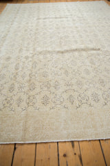 Oushak carpet with distressed blanched ivory field, minimalist charcoal vinery, secured edge.