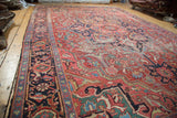 Distressed Ahar Heriz carpet in cherry red with navy border and time-softened patterns.