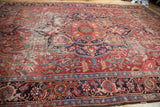 Distressed cherry red Ahar Heriz carpet, showcasing navy border and mallard green spandrels.