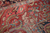 Distressed cherry red field, highlighting blue and gold arabesques, on an Ahar Heriz rug.