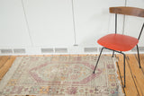 Distressed Oushak rug with faded violet hexagonal border and tattered fringe.