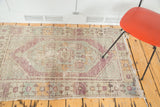 Distressed Oushak rug's right side, featuring faded violet border and tattered fringe.