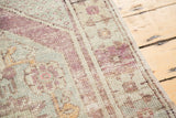 Distressed Oushak rug pile showing faded violet, mint, and ivory hues with visible knot heads.