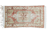 Distressed Oushak rug with faded geometric medallion, celadon green, cinnabar red, and earth tones.