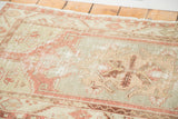 Distressed Oushak rug with faded cinnabar red and subdued celadon tribal patterns.