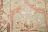 Faded celadon and brick red tribal patterns on a distressed hand-knotted Oushak rug.