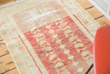 Distressed Oushak runner featuring faded cherry red, sand, and saffron floral and diamond motifs.