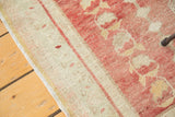 Close-up of distressed Oushak rug's side edge with faded blush and sand abrashes.
