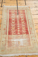 Localized distress, faded cherry red, and tattered fringe on vintage Oushak rug corner.
