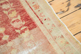 Close-up of distressed Oushak hand-knotted rug with worn pile, faded blush rose floral motifs.