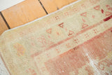 Distressed Oushak rug texture displaying sand, blush, and faded cherry red abrash.