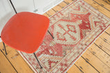 Faded cherry red tribal geometric patterns on a distressed Oushak rug.