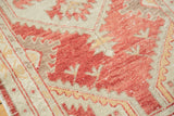 Distressed Oushak rug close-up, revealing geometric tribal patterns in faded cherry red and sand.