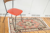 Faded blush rose and slate grey geometric motifs on a distressed Oushak rug corner.