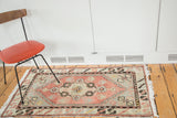 Distressed Oushak rug with faded blush rose field, slate grey-blue spandrel, and geometric motifs.