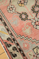 Distressed pile of a hand-knotted Oushak rug, showing blush rose, ivory, and geometric border details.