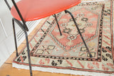 Blush rose and celadon green distressed Oushak rug corner with geometric spandrel design, ivory fringe.