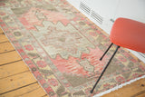 Distressed Oushak rug featuring a faded cranberry field, geometric medallion, and floral borders.