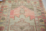 Distressed Oushak rug with faded cranberry field and pistachio green geometric medallion.