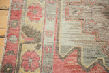 Distressed wool pile with faded cranberry floral and geometric grey patterns.