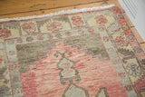 Corner detail of distressed Oushak rug showing faded cranberry field and geometric floral border.