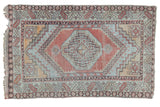 Distressed Oushak rug with geometric medallion in faded cinnabar red, grey, and warm beige tones.