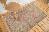 Distressed Oushak rug with geometric shadow medallion, hooked character, faded cinnabar and grey tones.