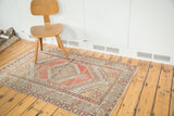 Distressed Oushak rug with geometric shadow medallion, hooked character, faded cinnabar red.