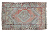 Distressed Oushak rug with geometric shadow medallion, faded cinnabar red, light blue, and beige.