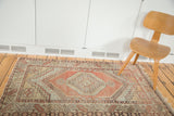 Distressed Oushak rug with geometric shadow medallion, hooked character, faded cinnabar red.