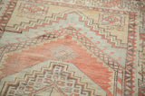 Distressed Turkish Oushak rug: faded cinnabar, grey, and beige geometric pattern detail.