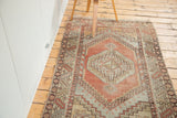 Faded cinnabar, grey, and beige hooked geometric patterns on distressed Oushak rug.