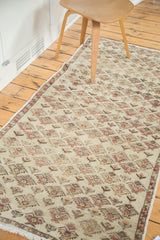 Distressed Oushak runner's repeating floral motif in washed beige, blush, and saffron tones.