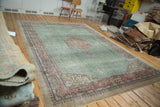 Distressed Oushak carpet with faded mallard green field and blush medallion, beige outer border.