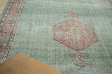 Distressed Oushak carpet with blush diamond medallion and patterned green relief field.