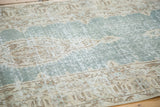 Distressed texture revealing faded teal green and sand geometric motifs.
