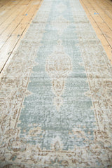 Distressed texture showing teal green and sand-colored geometric Oushak rug patterns.