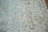 Textured pile of distressed Oushak carpet in faded aqua and blanched beige, with subtle motifs.