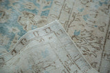 Distressed Oushak rug corner revealing faded aqua pattern and hand-knotted foundation.