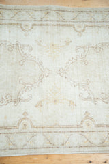Faded ivory and dusty saffron patterns on the distressed Oushak rug pile.