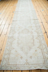 Distressed Oushak rug runner with a secured fringed end and muted ivory pattern.