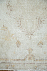 Antique ivory Oushak runner with faded saffron yellow patterns, worn pile, and fringe.