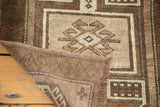 Hand-knotted Oushak rug corner, revealing beige and brown geometric squares and woven back.