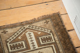 Hand-knotted Oushak rug corner revealing beige, sand, and brown geometric squares with fringe.